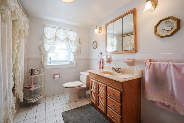 full bath featuring toilet, vanity, wainscoting, tile patterned floors, and tile walls