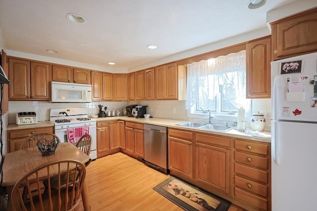 kitchen with a sink, white appliances, light wood-style flooring, and light countertops