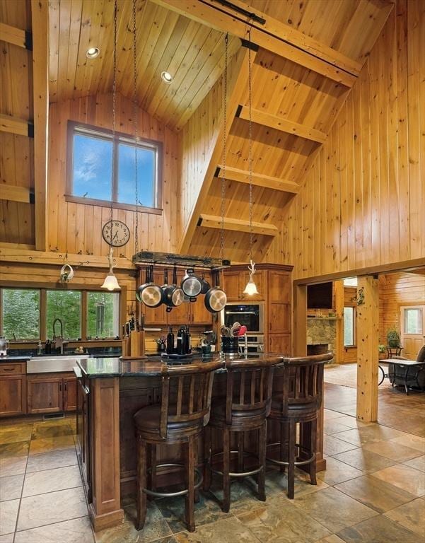 4 Paddock Rd, Rutland, MA 01543 - kitchen featuring high vaulted ceiling, wood walls, wood ceiling with exposed beams, dark countertops, and brown cabinetry
