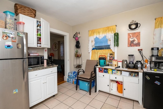 kitchen with dark stone countertops, white cabinetry, light tile patterned floors, and appliances with stainless steel finishes