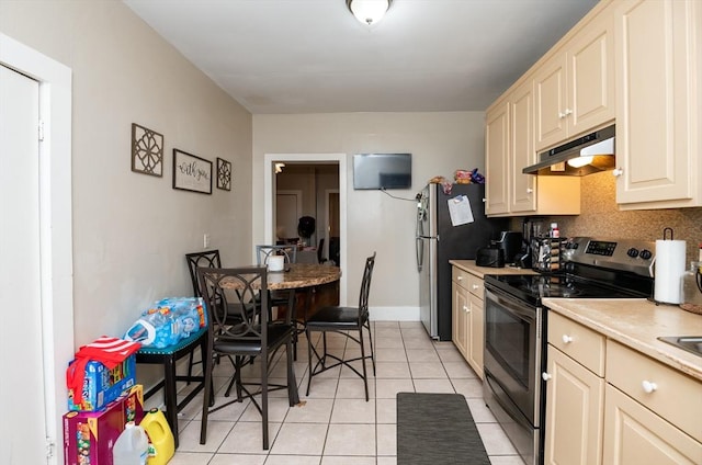 kitchen featuring cream cabinetry, light tile patterned floors, backsplash, and stainless steel appliances