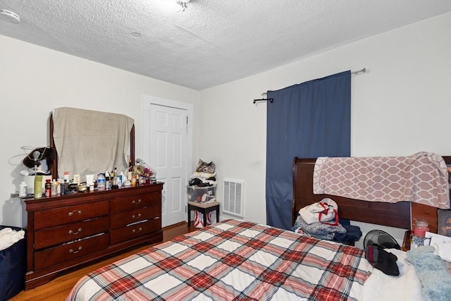 bedroom featuring light hardwood / wood-style flooring and a textured ceiling