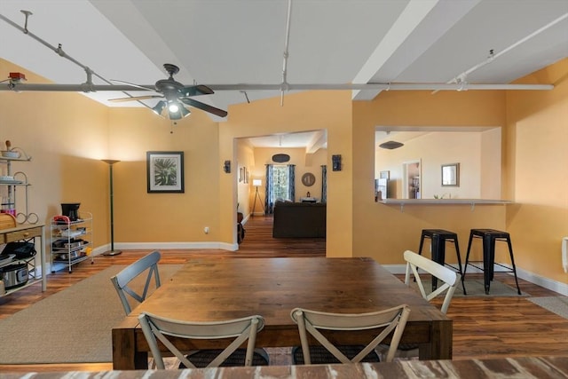 dining room with a ceiling fan, rail lighting, wood finished floors, and baseboards
