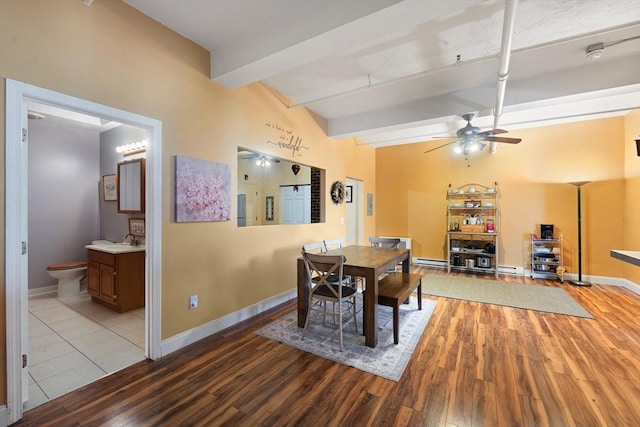 dining room with baseboards, wood finished floors, a baseboard heating unit, ceiling fan, and beam ceiling