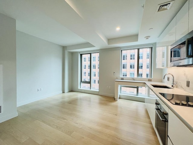 kitchen featuring sink, stainless steel appliances, white cabinetry, and light hardwood / wood-style floors