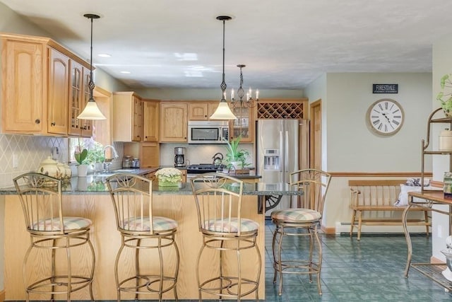 kitchen featuring pendant lighting, sink, stainless steel appliances, a kitchen bar, and decorative backsplash