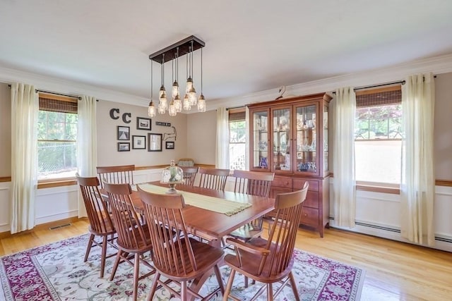 dining room with crown molding, a baseboard heating unit, and light wood-type flooring