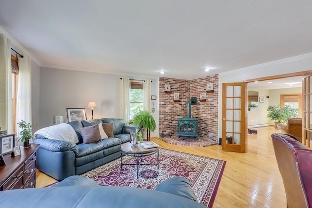 living room featuring ornamental molding, a wood stove, light hardwood / wood-style floors, and french doors