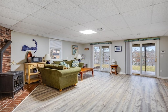 living room with hardwood / wood-style flooring, a drop ceiling, and a wood stove