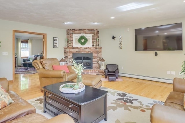 living room featuring a brick fireplace, light wood-type flooring, and baseboard heating