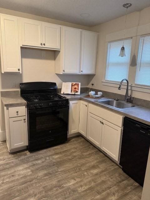 kitchen featuring dark hardwood / wood-style floors, pendant lighting, black appliances, sink, and white cabinets