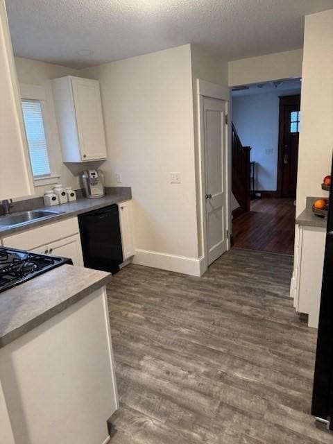 kitchen featuring a textured ceiling, white cabinets, black dishwasher, sink, and dark hardwood / wood-style floors