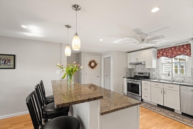 24 Hodgkins Dr, Ipswich, MA 01938 - kitchen with appliances with stainless steel finishes, a sink, white cabinetry, light wood-type flooring, and under cabinet range hood