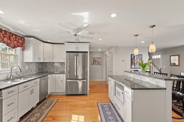 24 Hodgkins Dr, Ipswich, MA 01938 - kitchen with a breakfast bar, ceiling fan, white cabinets, a sink, and stainless steel appliances