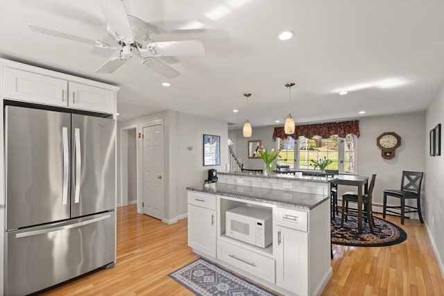 24 Hodgkins Dr, Ipswich, MA 01938 - kitchen with ceiling fan, freestanding refrigerator, white microwave, light wood-style floors, and white cabinetry