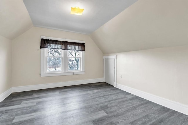 additional living space featuring vaulted ceiling and dark wood-type flooring