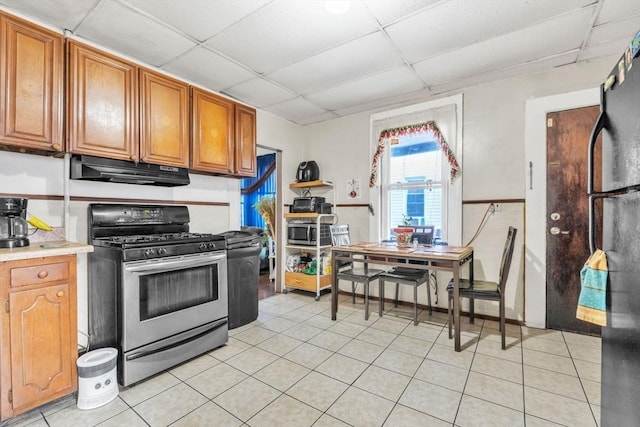 kitchen featuring stainless steel appliances, light tile patterned floors, and a drop ceiling