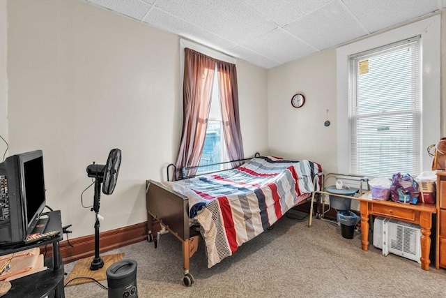 carpeted bedroom featuring a drop ceiling