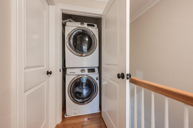 laundry area with hardwood / wood-style flooring, stacked washer / drying machine, and ornamental molding