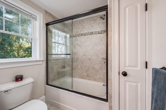 bathroom featuring bath / shower combo with glass door and toilet