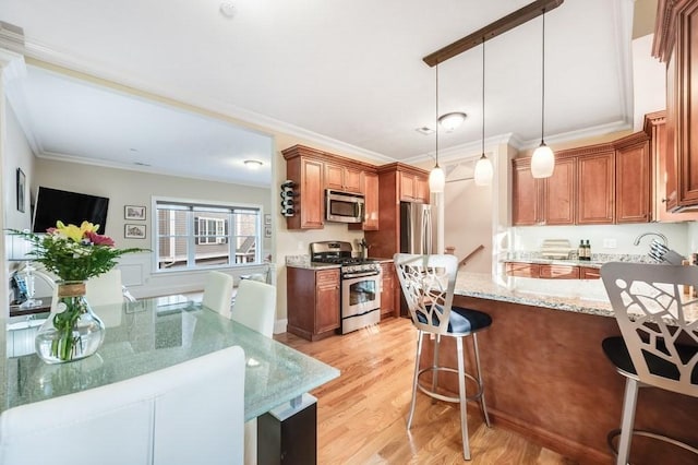 kitchen with light stone counters, ornamental molding, stainless steel appliances, light hardwood / wood-style floors, and hanging light fixtures