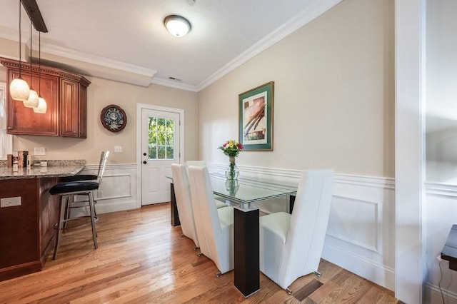 dining room with light hardwood / wood-style flooring and ornamental molding