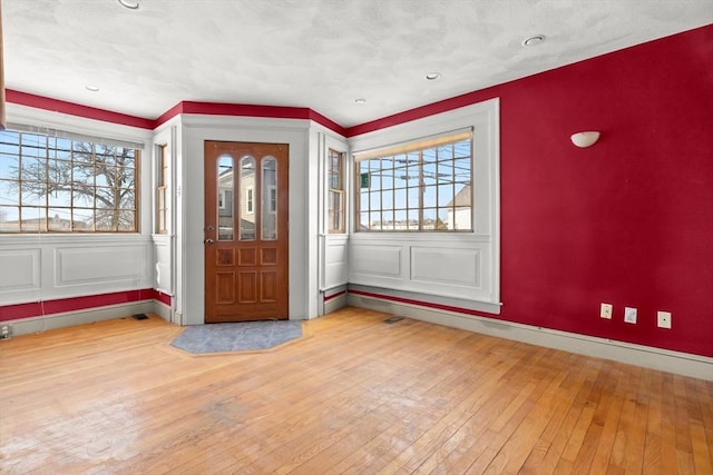 entryway featuring plenty of natural light, an accent wall, baseboards, and hardwood / wood-style floors