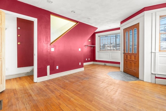 foyer entrance featuring hardwood / wood-style flooring, visible vents, baseboards, and a wealth of natural light