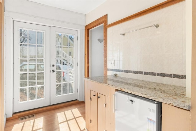 doorway featuring light wood finished floors, french doors, and visible vents