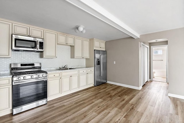 100 Magnolia Ave Unit 26, Lynn, MA 01904 - kitchen with appliances with stainless steel finishes, cream cabinets, a sink, light wood finished floors, and backsplash