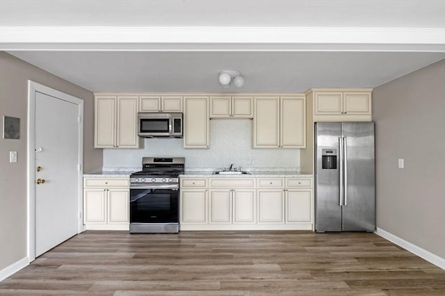 100 Magnolia Ave Unit 26, Lynn, MA 01904 - kitchen with stainless steel appliances, cream cabinets, a sink, light wood-style floors, and baseboards