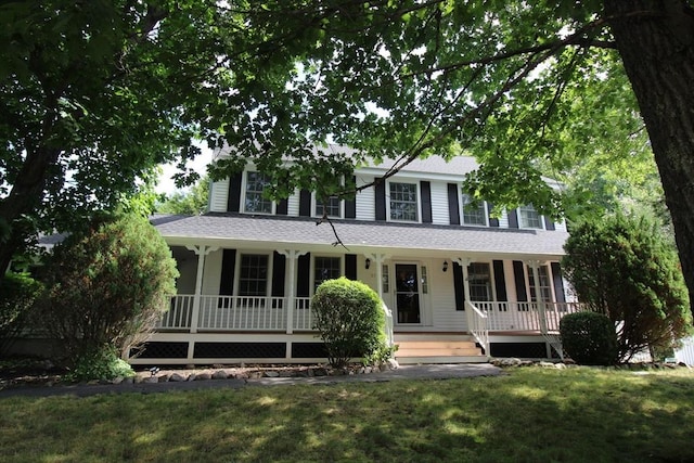 colonial home featuring a shingled roof, covered porch, and a front yard