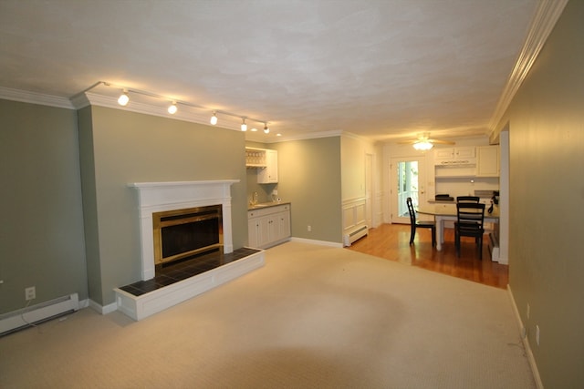 unfurnished living room with ornamental molding, light hardwood / wood-style flooring, a tile fireplace, baseboard heating, and ceiling fan