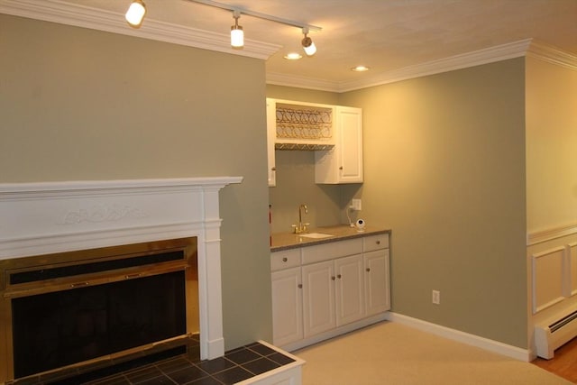 bar with track lighting, wet bar, a glass covered fireplace, a sink, and a baseboard radiator