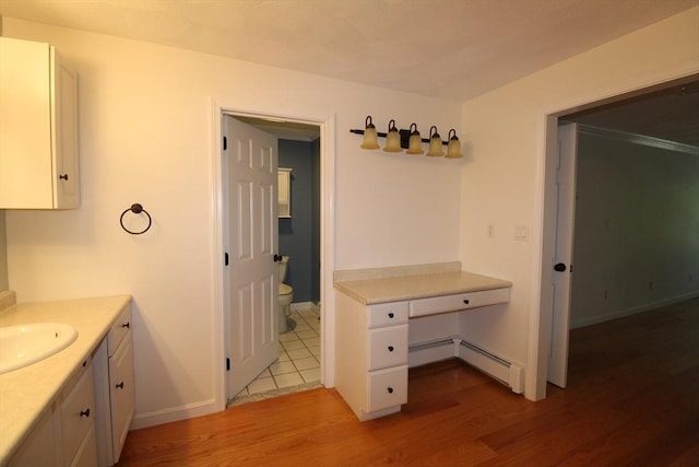 bathroom with baseboards, toilet, baseboard heating, vanity, and wood finished floors