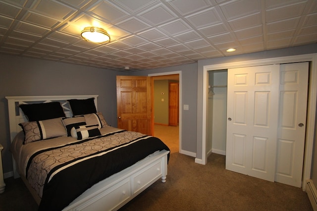 carpeted bedroom with a closet and a baseboard heating unit