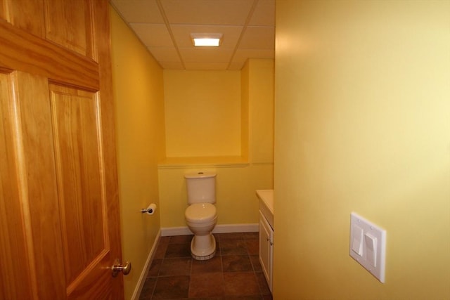 bathroom with vanity, baseboards, toilet, visible vents, and a drop ceiling