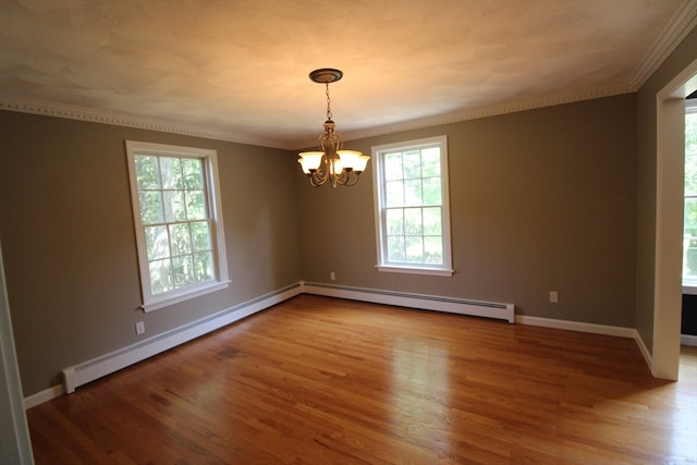 spare room featuring a baseboard heating unit, ornamental molding, a notable chandelier, and hardwood / wood-style floors