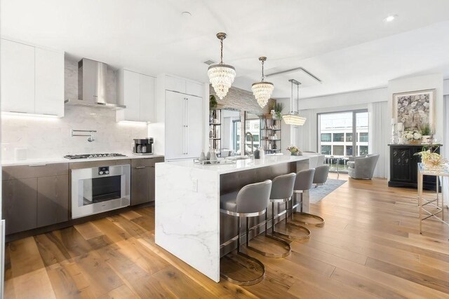 300 Blvd 3I, Boston, MA 02210 - kitchen featuring wall oven, wall chimney range hood, modern cabinets, a breakfast bar area, and decorative backsplash