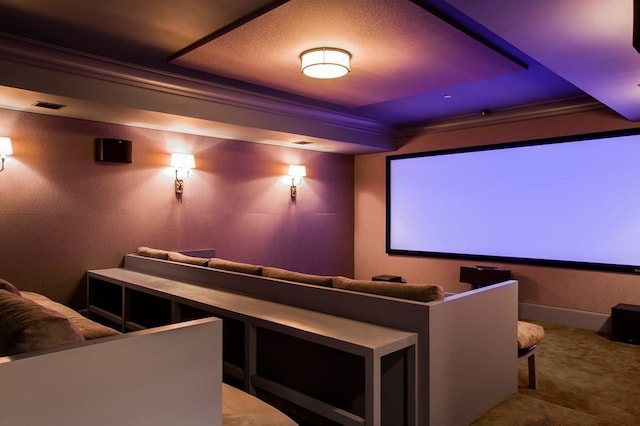 carpeted cinema room featuring crown molding and a tray ceiling