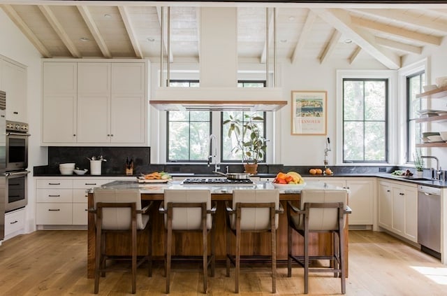 kitchen featuring a kitchen bar, a center island, white cabinets, and vaulted ceiling with beams