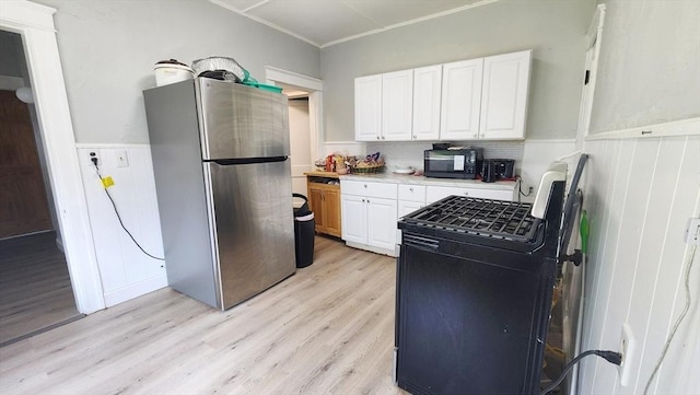 132 Institute Rd, Worcester, MA 01602 - kitchen with black appliances, light wood-style flooring, white cabinets, wainscoting, and light countertops