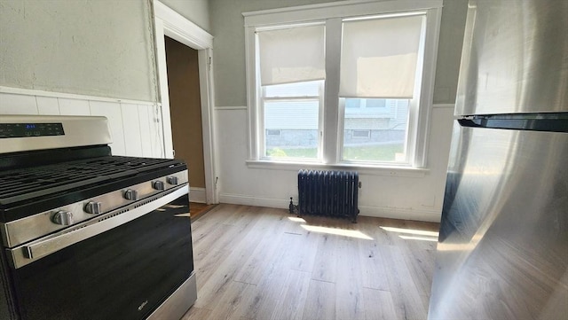 132 Institute Rd, Worcester, MA 01602 - kitchen with appliances with stainless steel finishes, radiator, light wood-style floors, and a wainscoted wall