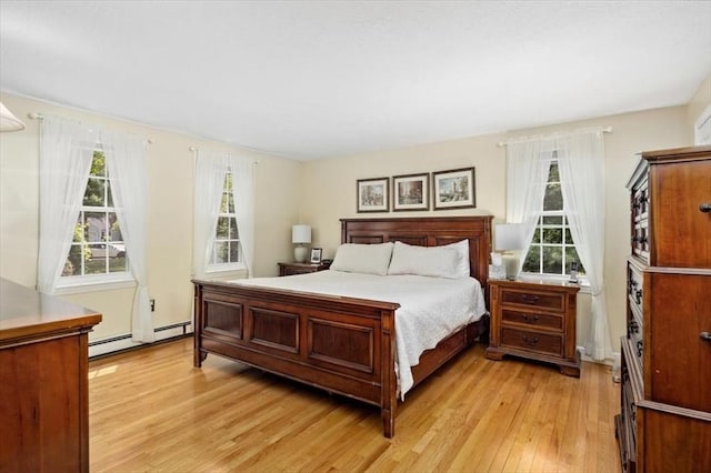 bedroom featuring a baseboard heating unit, light wood-style flooring, and multiple windows