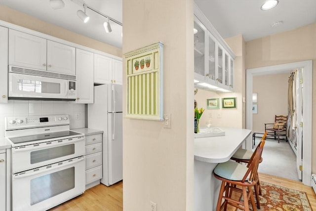 5 Myrtle St Unit 3, Boston, MA 02114 - kitchen featuring white appliances, a breakfast bar, white cabinets, glass insert cabinets, and light countertops