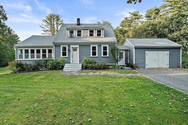 view of front of property featuring an outbuilding, a chimney, a front yard, and aphalt driveway