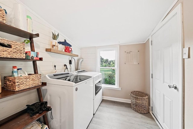washroom featuring baseboards, laundry area, light wood-style flooring, and washing machine and clothes dryer