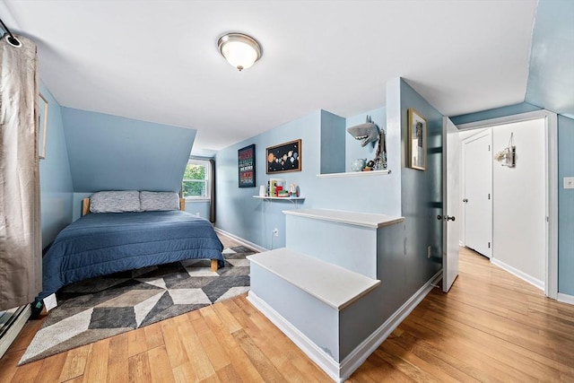 bedroom featuring baseboards, a baseboard heating unit, vaulted ceiling, and hardwood / wood-style floors