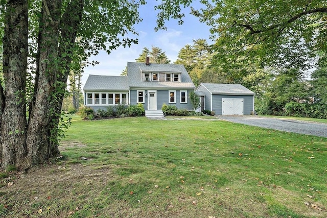 view of front of house with a detached garage, a chimney, an outbuilding, and a front lawn
