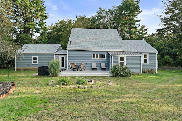 rear view of house featuring a lawn, a chimney, and roof with shingles